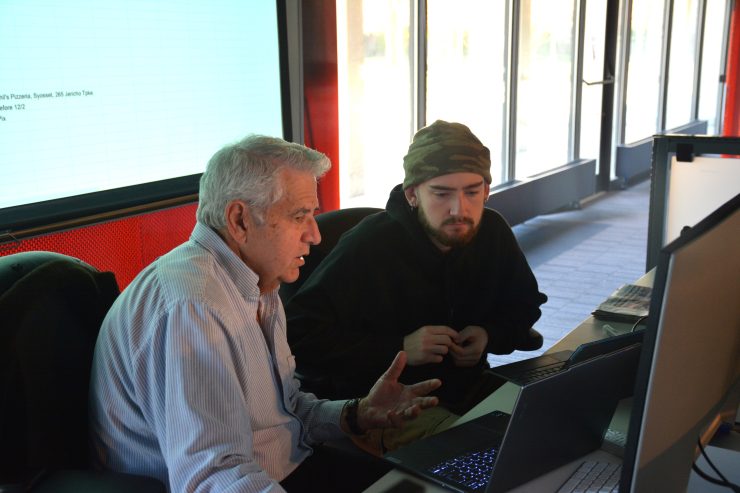 Professor George Giokas works with a student at a computer in the SoCJ's professional newsroom class