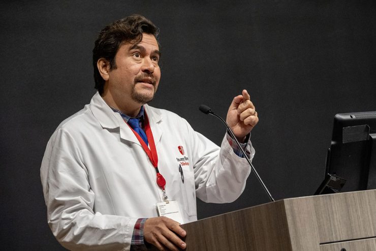 Male doctor in a white coat giving a lecture at a podium with a microphone