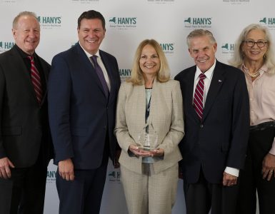 Group of five professionals posing for a photo at a HANYS event; the woman in the center holds a glass award.